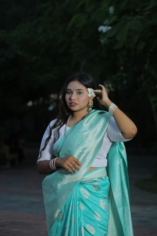 a beautiful young woman in a blue sari holding up her ear