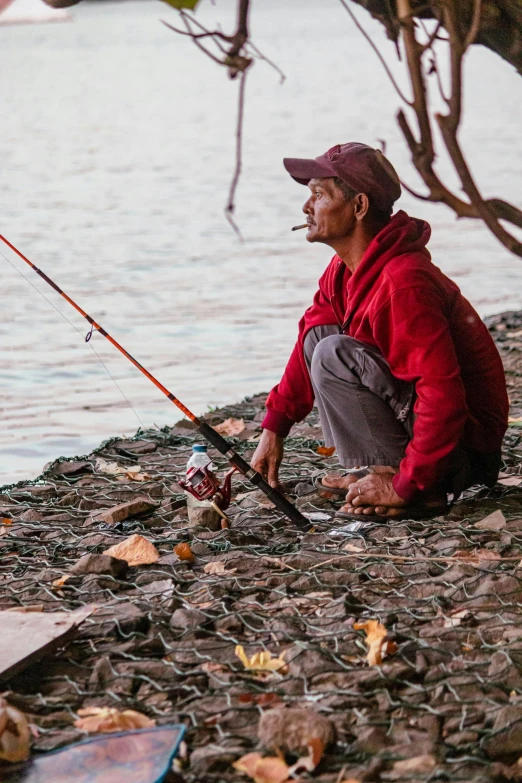 a man is sitting on the side of a lake while fishing