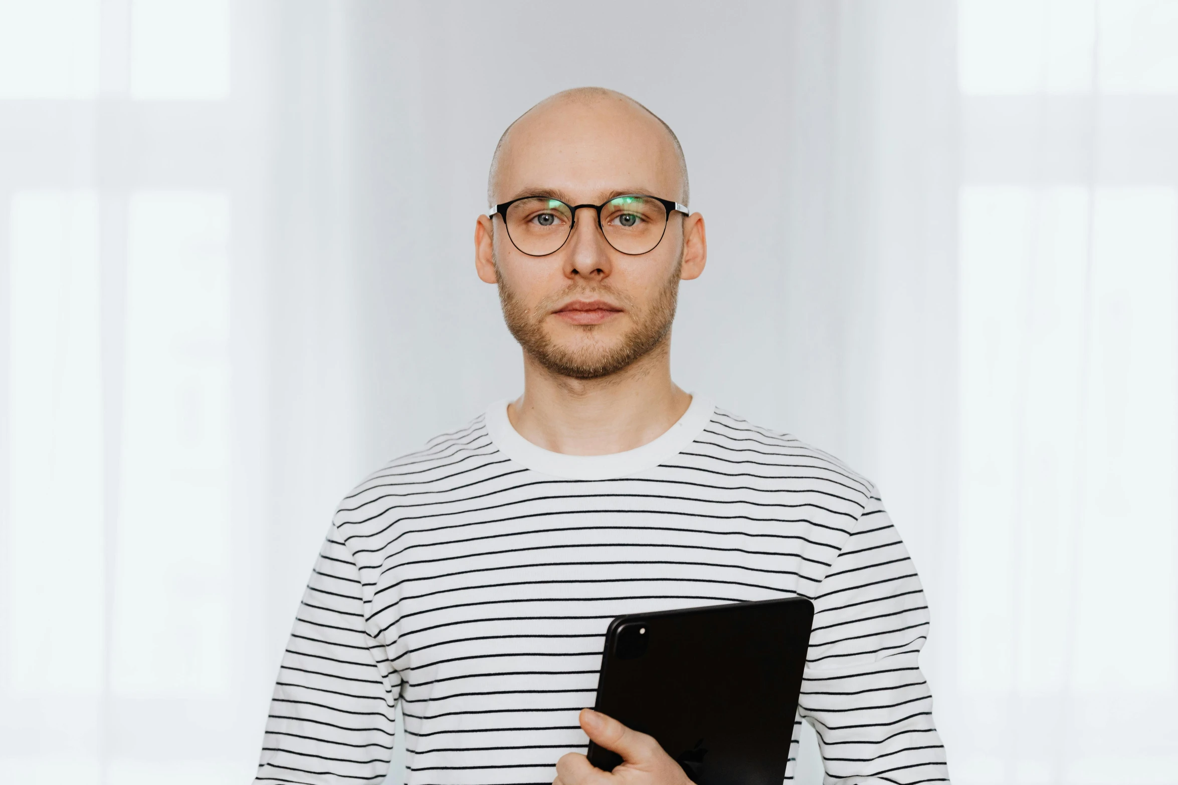 bald man holding tablet in front of his face