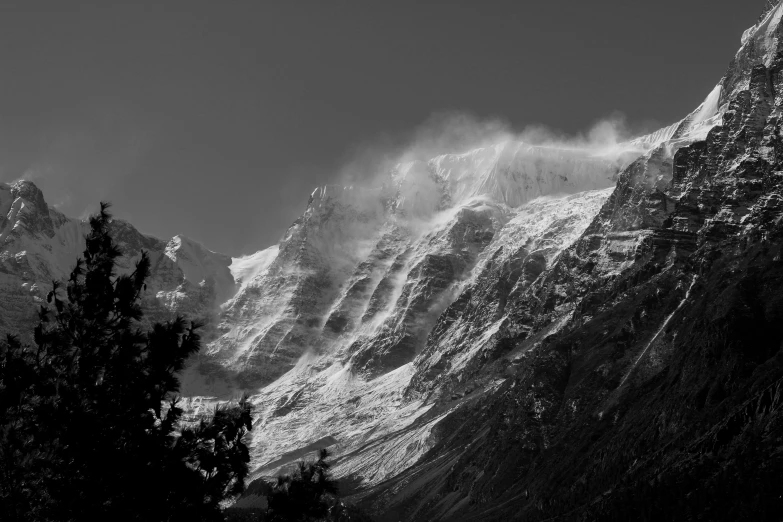 some very tall mountains covered in snow next to some trees