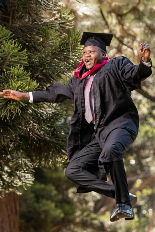 a man in a graduation cap and gown is jumping off a ledge