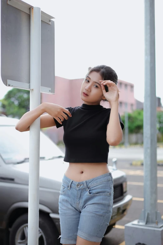 a woman standing next to a traffic sign on the side of a road