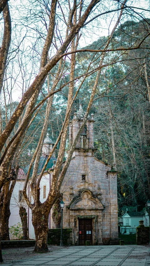 a stone church surrounded by trees and benches