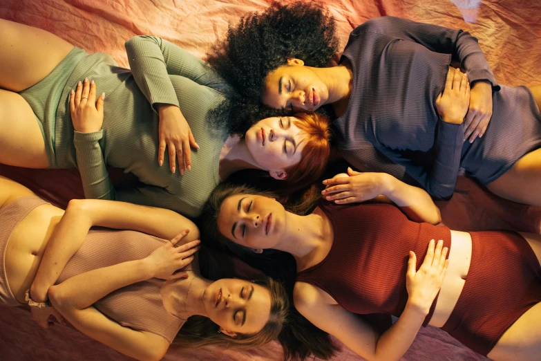 three beautiful young ladies laying in a circle on top of a bed