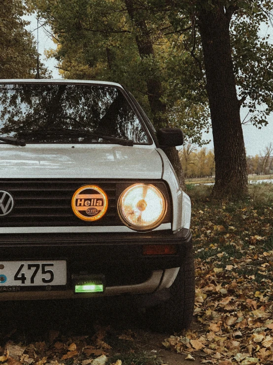 the front end of a white car with the light on