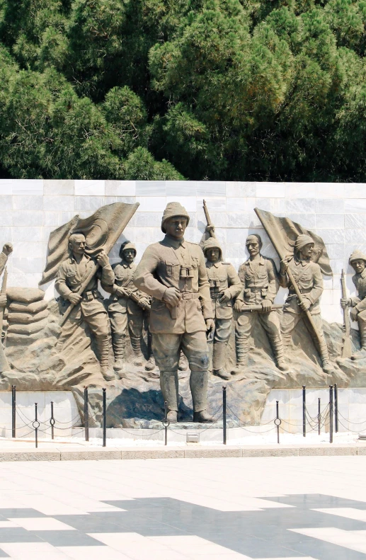 a statue of soldiers holds flags as they walk past a large mural