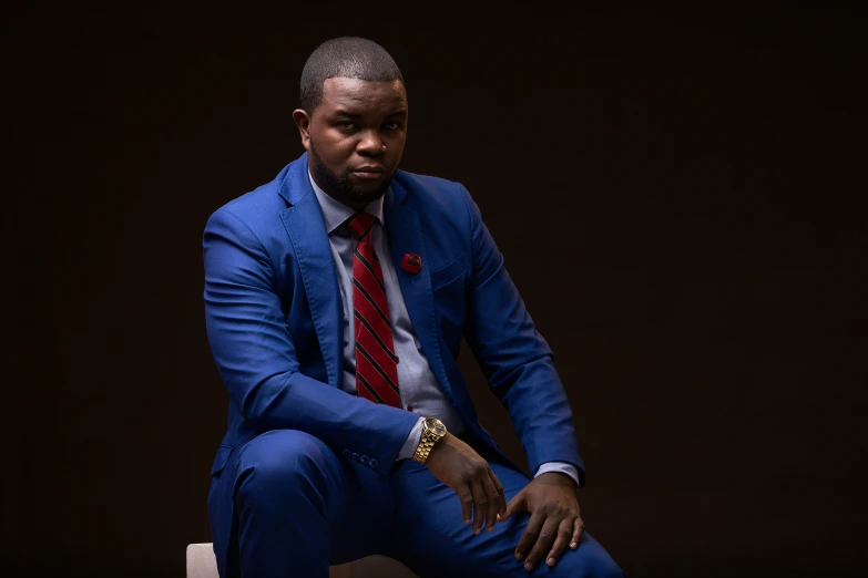 a man sitting on a white chair in blue suit