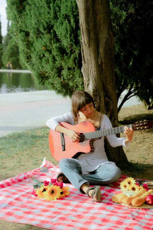 girl in white shirt playing the guitar at picnic