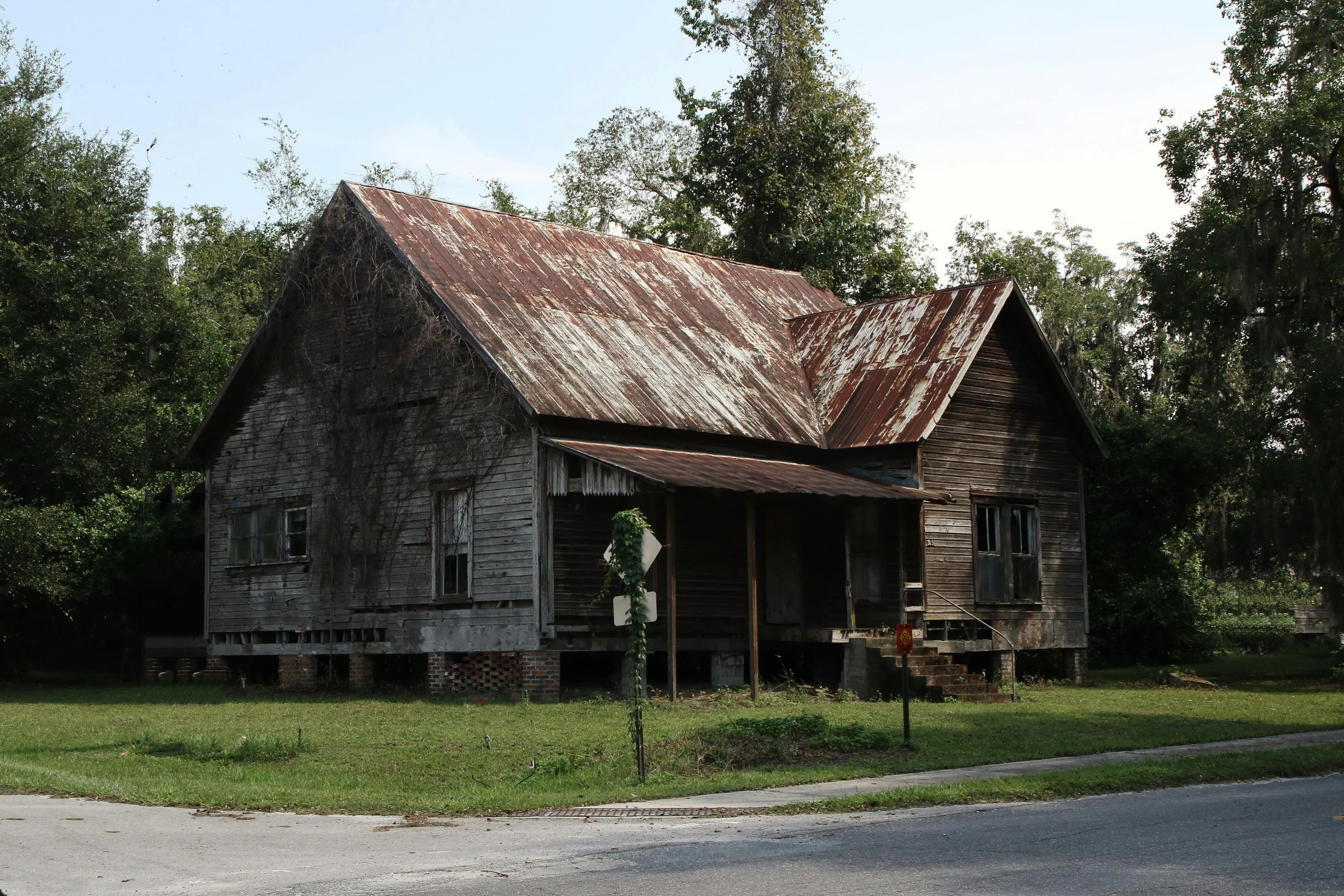 an old weathered house stands next to a rural road