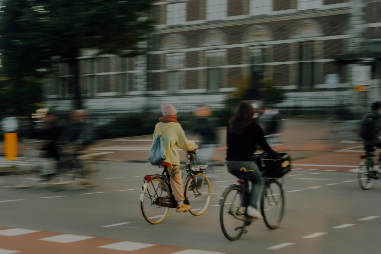 two women riding bicycles through the street in a crosswalk