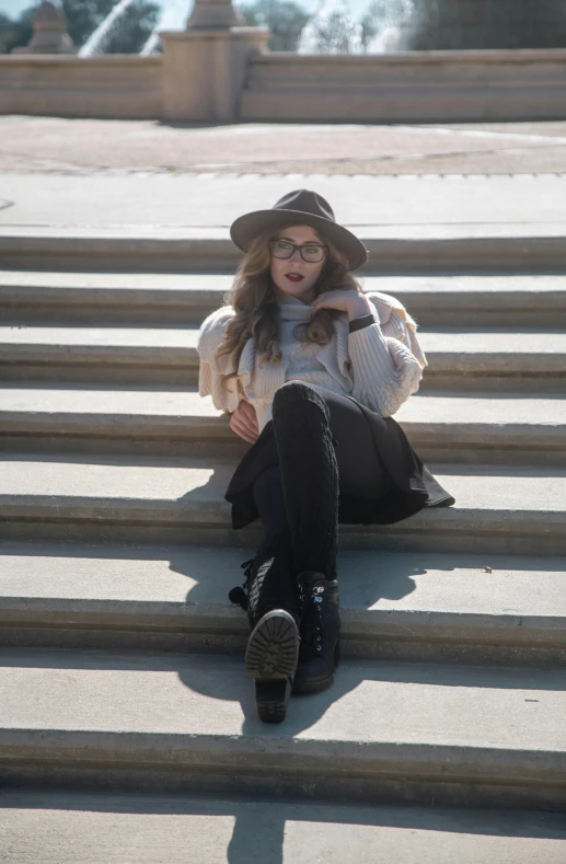 a woman is sitting down on some stairs wearing glasses