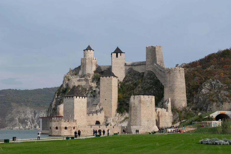 people are walking along the grass near an old castle