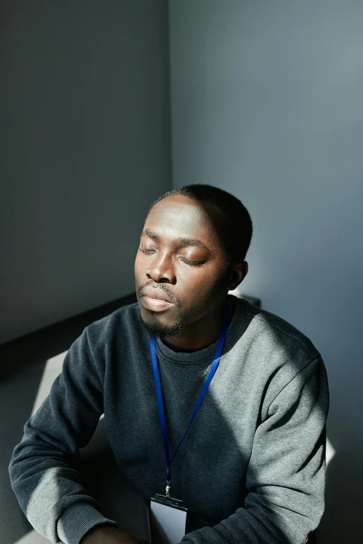 man is sitting by a wall while listening to his music