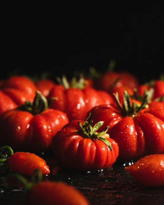 a bunch of red tomatoes on a counter top with droplets on them