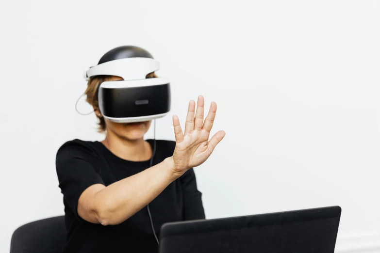 a woman uses a virtual headset while using a laptop computer