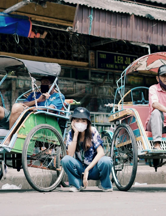 people sitting in rickshaws on the side of a road