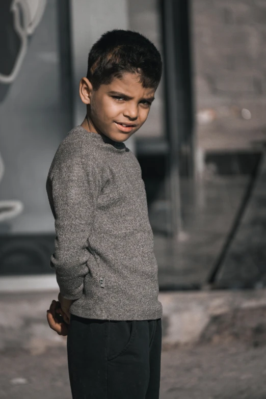 a boy in grey sweater standing on the street
