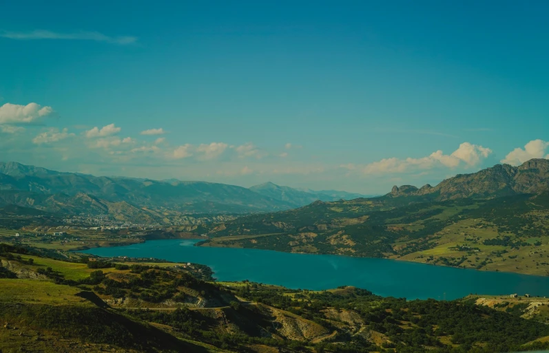 a scenic scene with water, mountains and cloudy skies