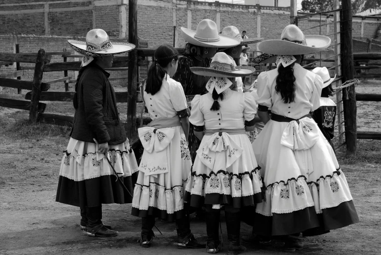 a group of young women in long skirts are standing with hats on their head