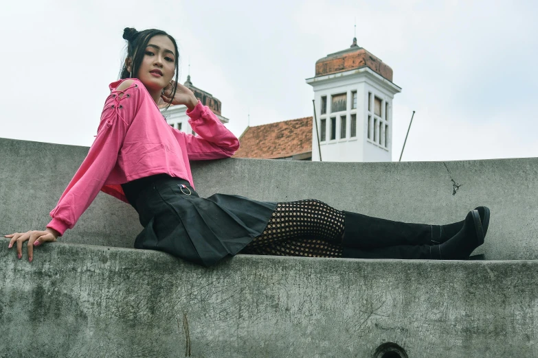 a woman is sitting on the side of a stone wall