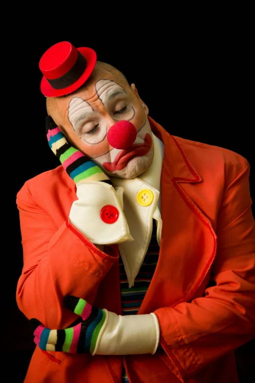 a clown wearing a red suit and hat with a creepy clown makeup on