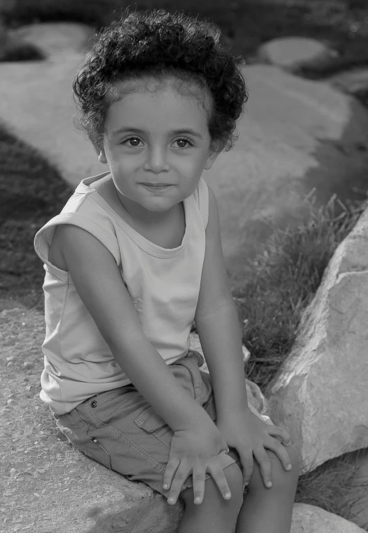 the little girl sits on a rock and smiles