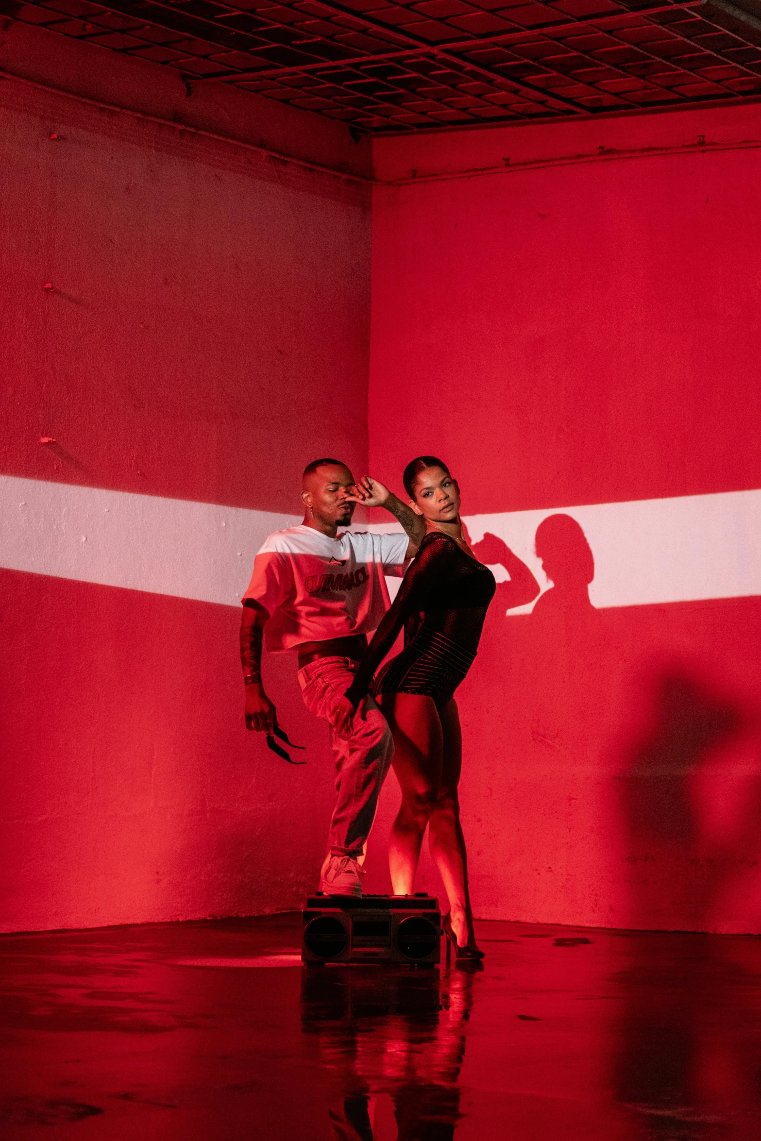 the dance couple is silhouetted against a red and white wall