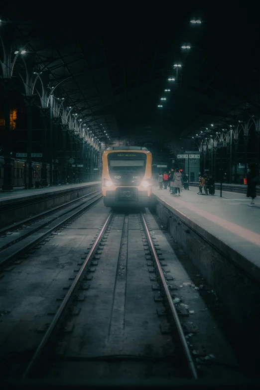 the train is pulling up to a station in the dark