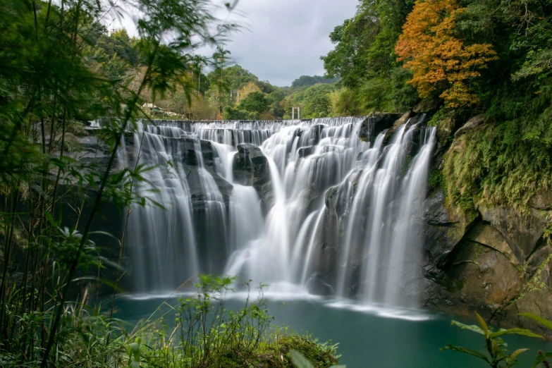 a waterfall surrounded by greenery next to a blue river