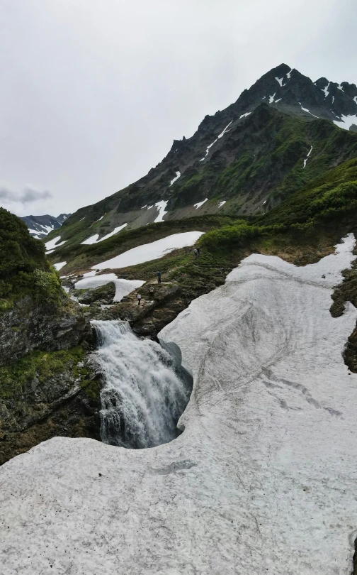 an open, snowy field next to a mountain with snow on it