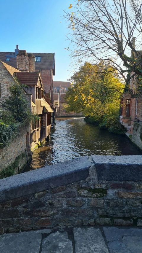 a river runs alongside a stone wall and buildings