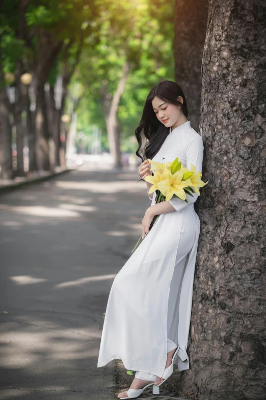 a beautiful woman in white sitting on a tree trunk