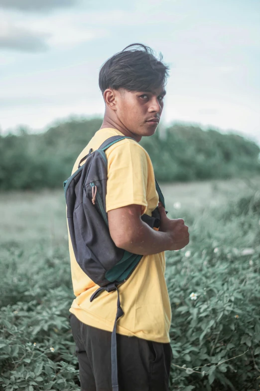 a young man is standing in a field with a backpack on