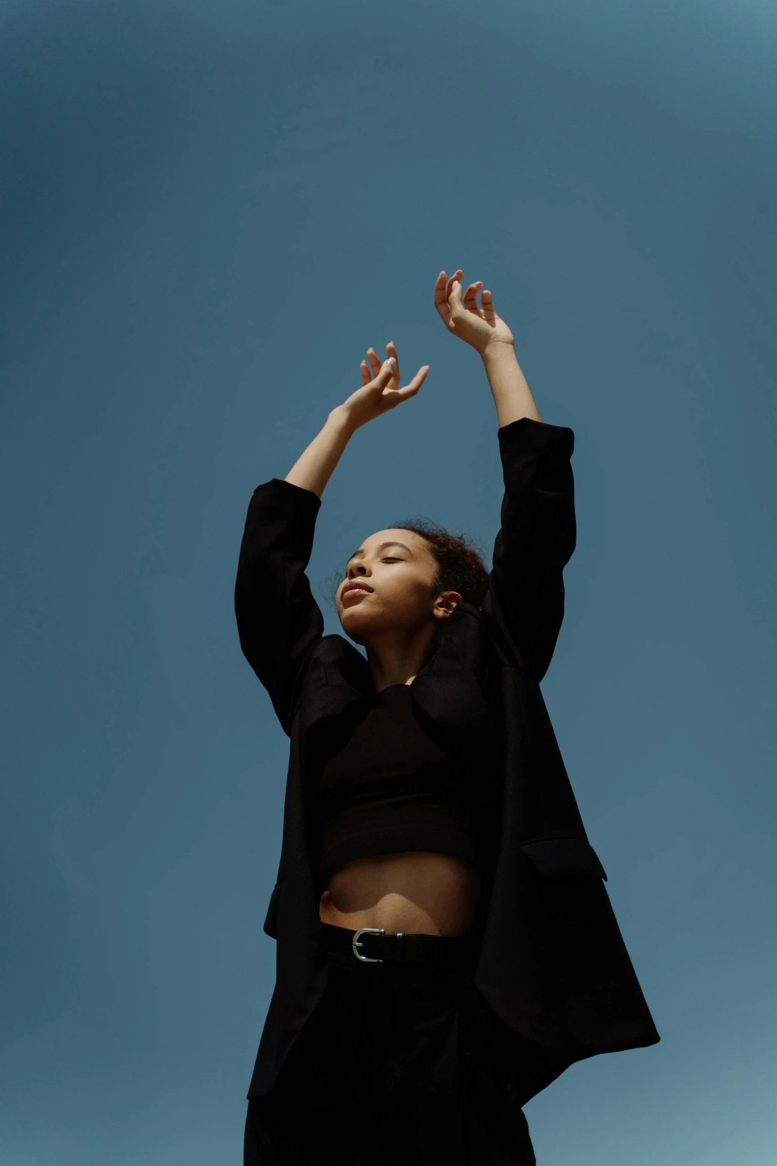 an african american woman in high heels raises her arms up into the air