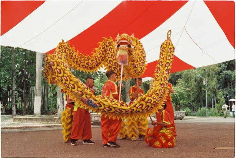 two people standing next to a dragon dance at the park