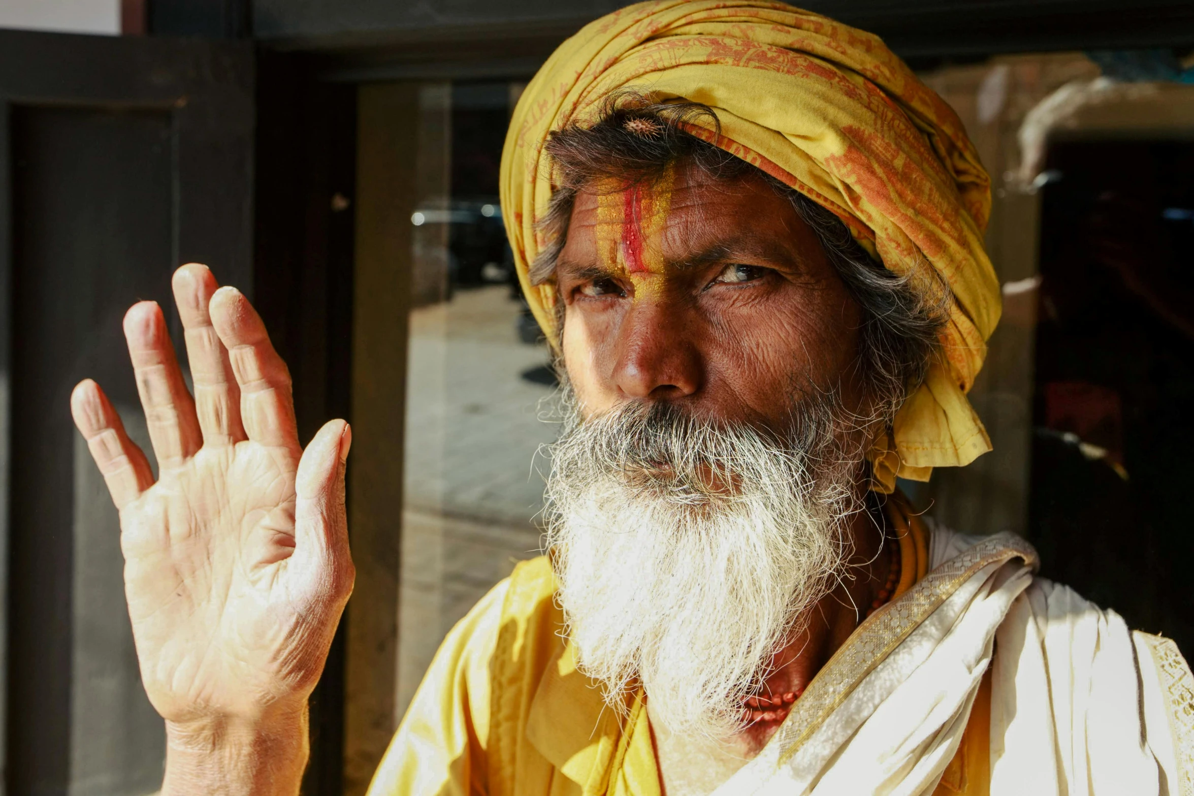 an older man wearing yellow is waving