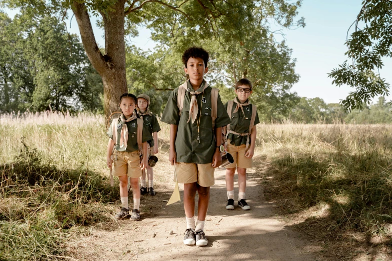 a man with three s wearing scout uniforms walking in the woods