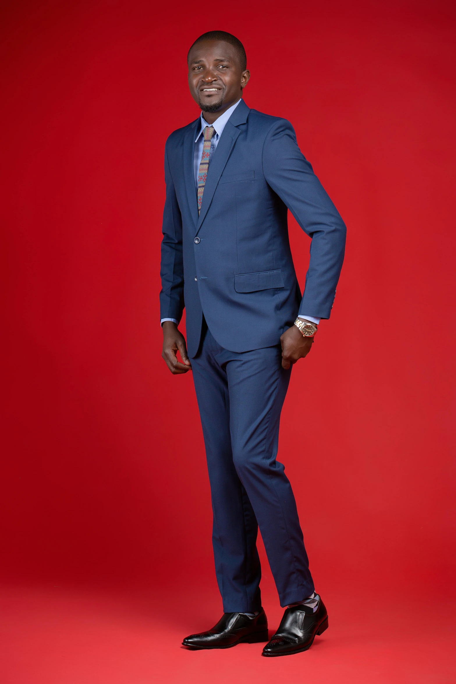 a man in a suit standing next to a red wall