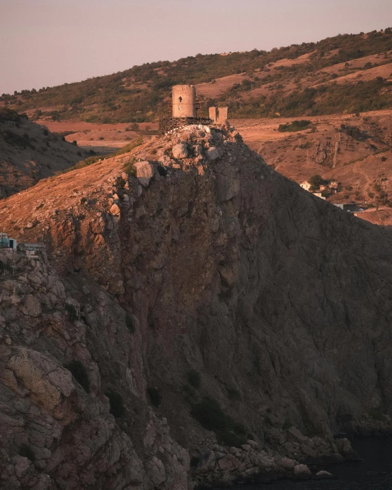 a house sits on a rocky cliff top with a mountain background