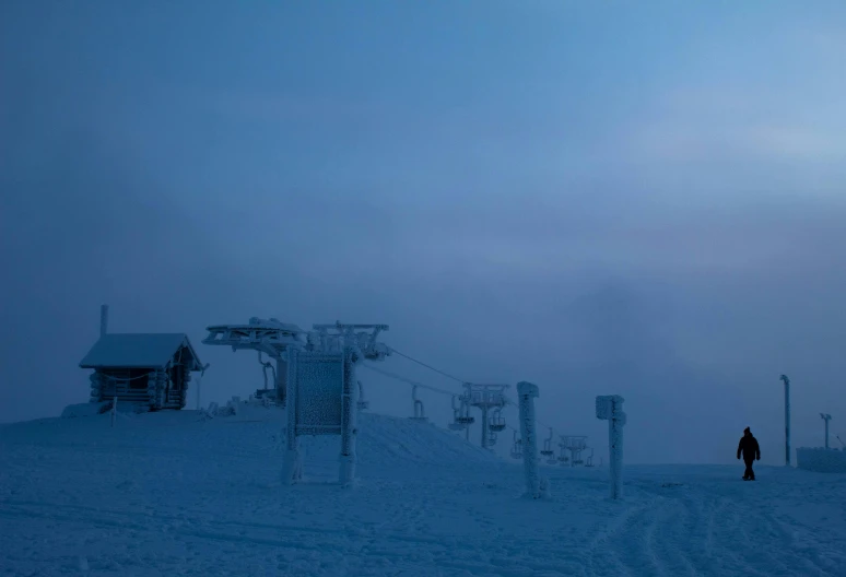 man standing next to the ski lift at dusk