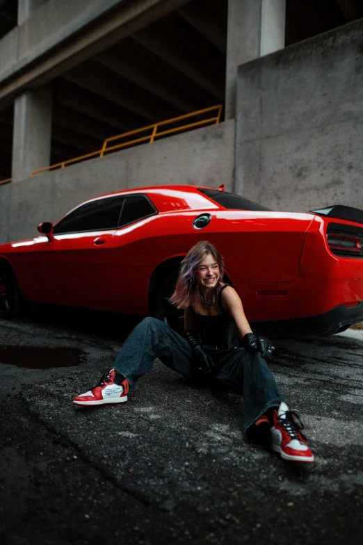 a woman is sitting near a red sports car