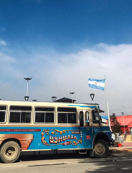 an old bus parked in front of a flagpole