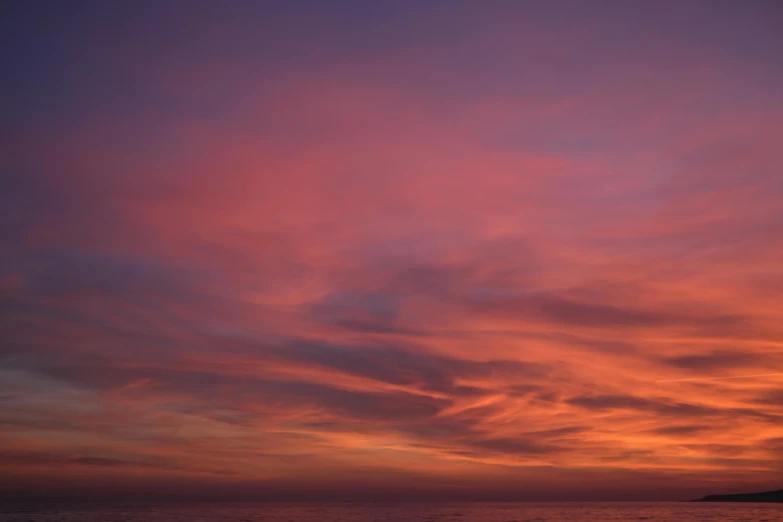 the setting sun reflects off in the clouds above the water