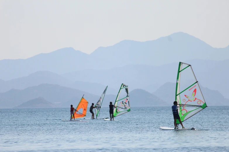 three people in the water with sails and one being pulled behind them