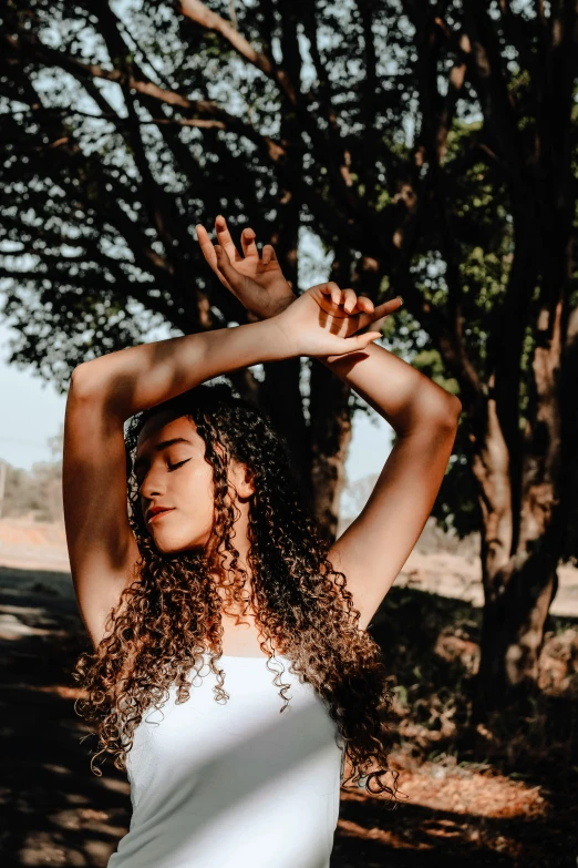 a woman stands in the middle of a forest with her hands behind her head