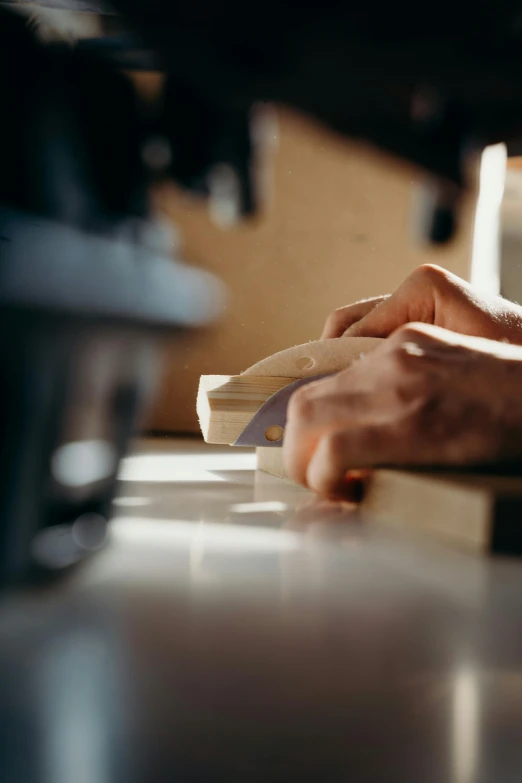 a pair of hands are placing a wooden block of wood on a counter