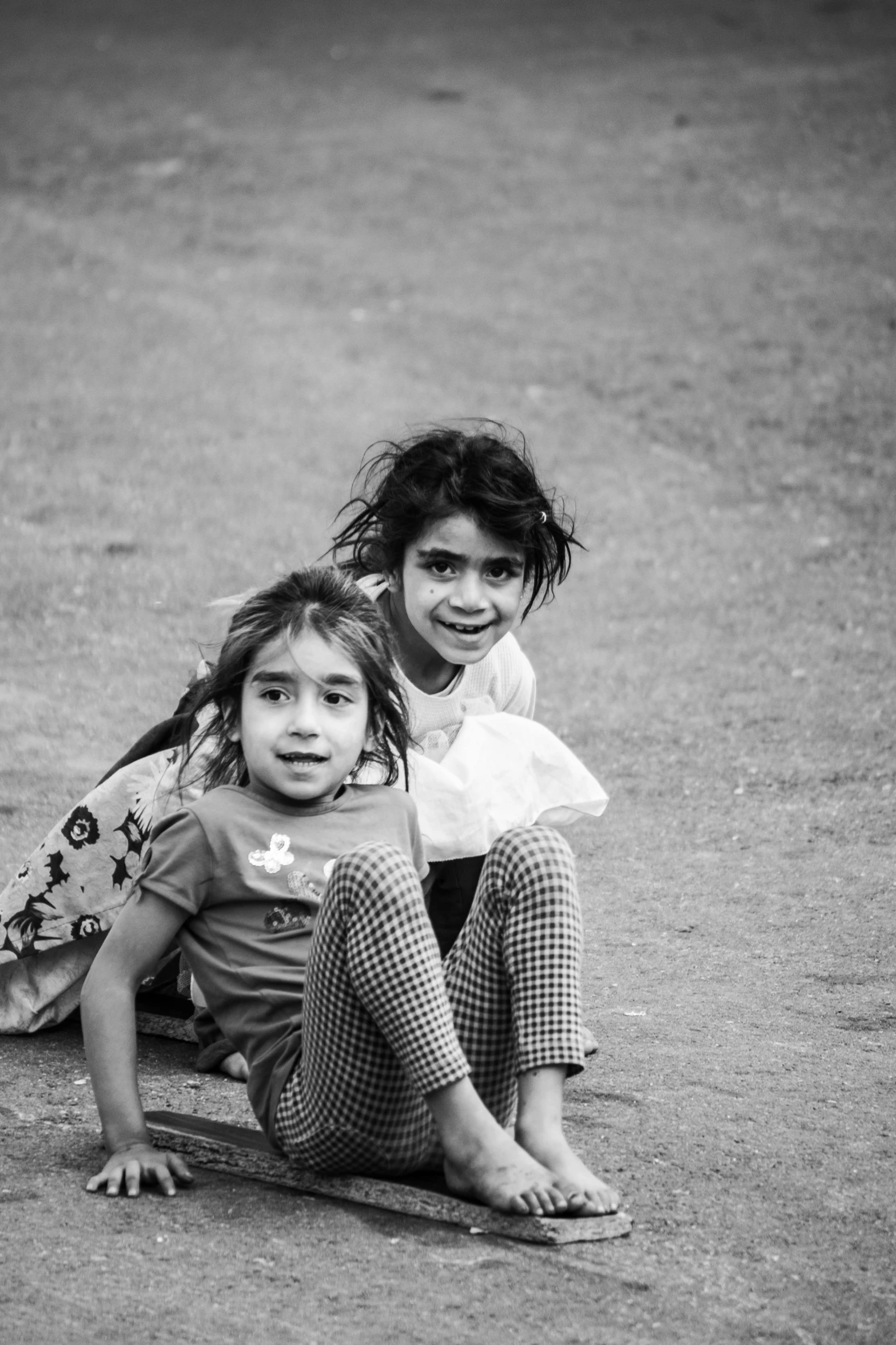 black and white image of two children lying down on the ground