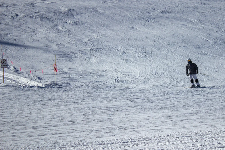 the skier in black is approaching the snowy hill