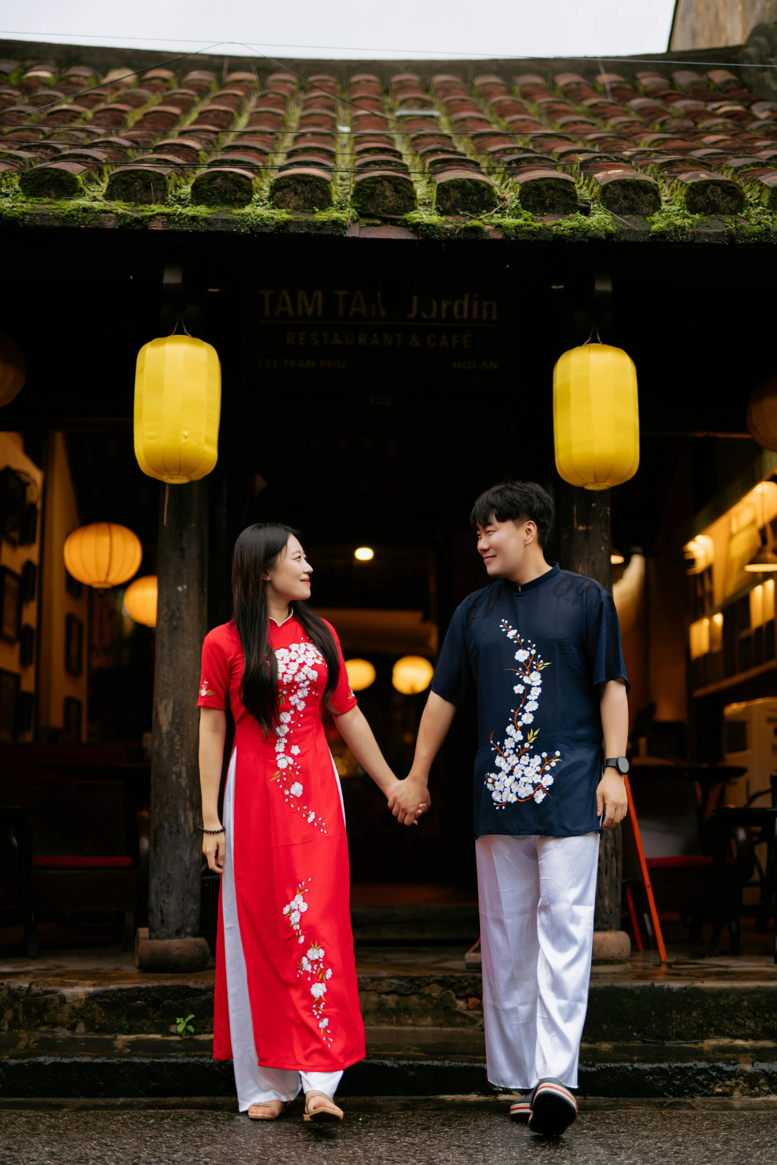 a young couple stands on some steps near lanterns