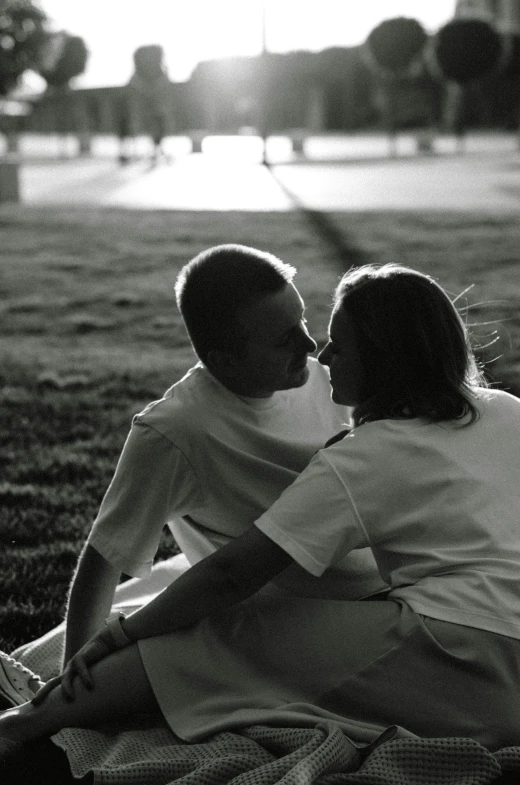 an affectionate couple are sitting on the grass